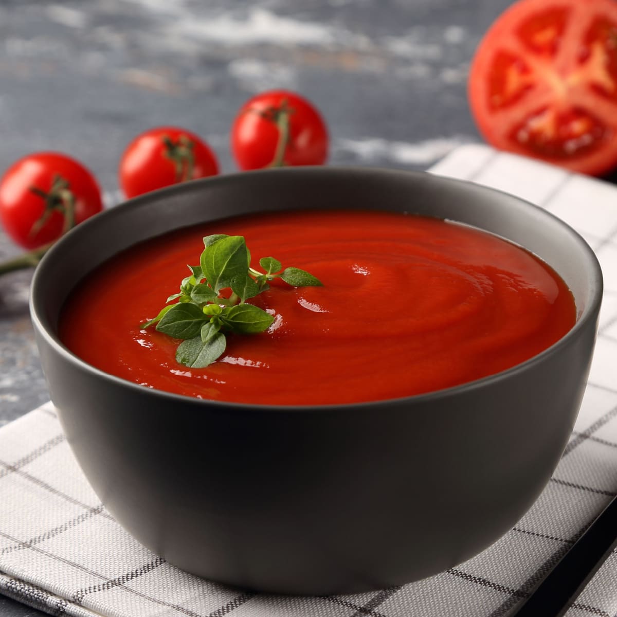 A Bowl of Tomato Soup and Fresh Tomatoes on a Wooden Table