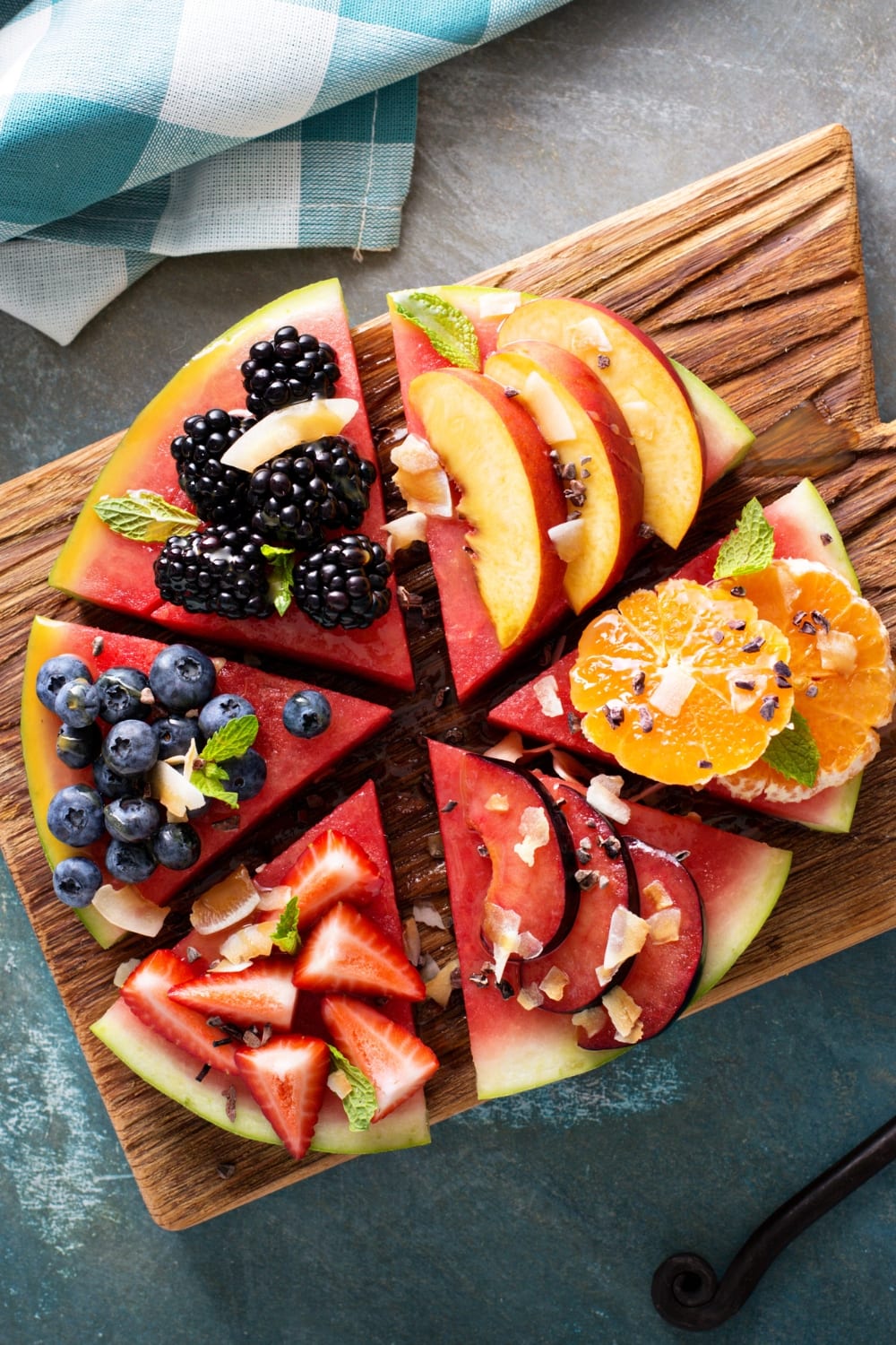 30 Fresh Watermelon Recipes (Easy Ideas) featuring Watermelon Pizza Topped with Blackberries, Plums, Oranges, Peaches, Blueberries, Strawberries, Toasted Coconut, and Mint on a Wooden Cutting Board