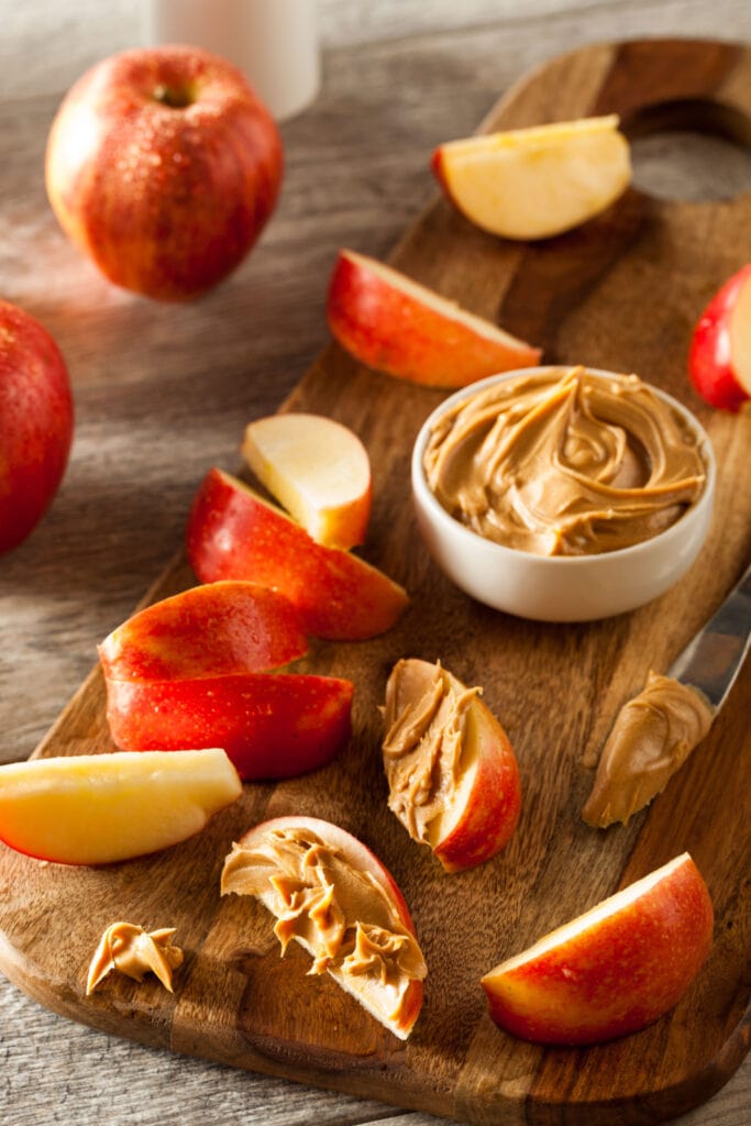 Apples with Peanut Butter on a Wooden Cutting Board