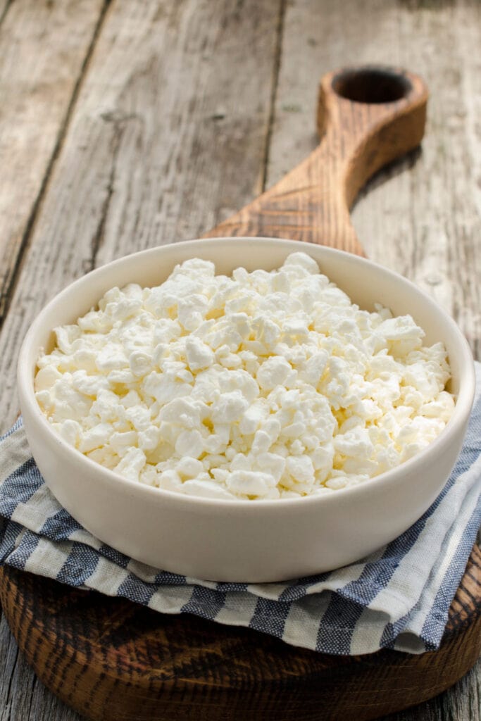 Bowl of Cottage Cheese on a Wooden Board