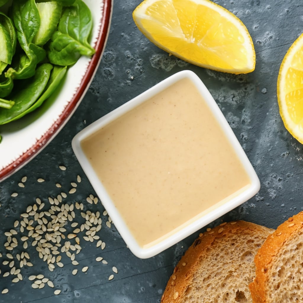 Bowl of Tasty Tahini with Lemon, Bread, Sesame Seeds and Spinach