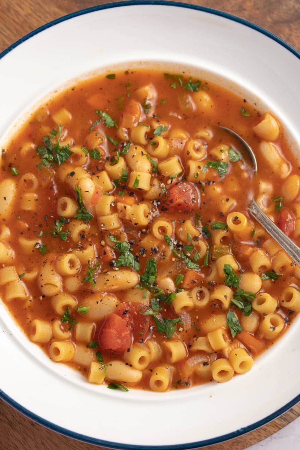 Bowl of warm pasta fagioli soup with diced tomatoes and parsley. 