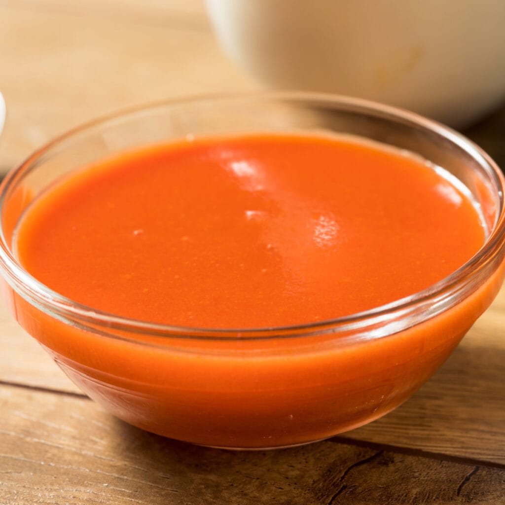A Bowl of Spicy Buffalo Sauce on a Wooden Table