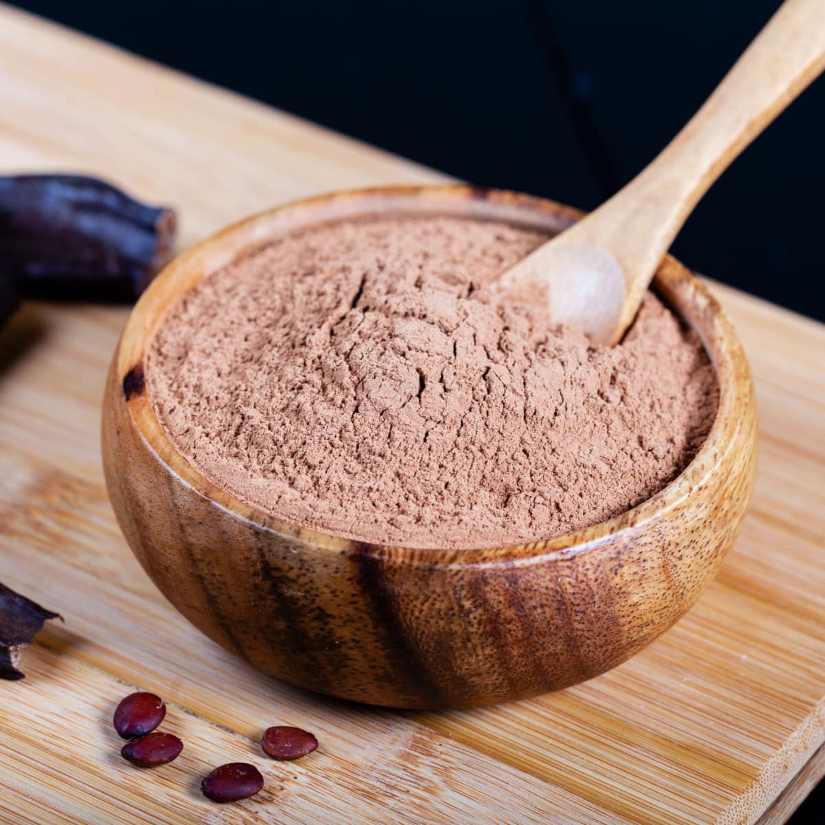 Bowl of Carob Powder and Carob Pods on a Wooden Table
