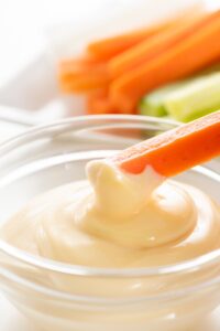 Carrot Stick Dipped in a Bowl of Mayonnaise
