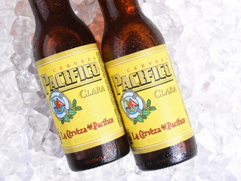 Two Condensation-Covered Glass Bottles of Cerveza Pacifico Sitting on Ice
