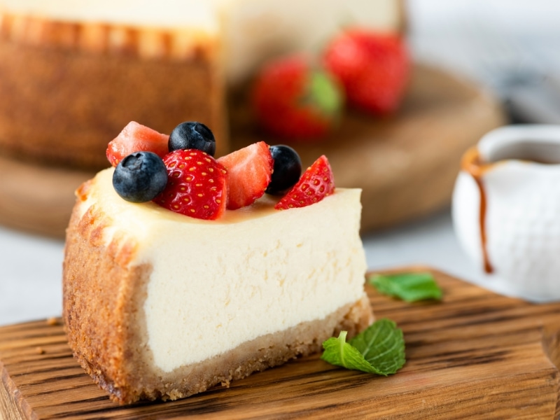 Cheesecake Slice Topped With Fresh Berries on a Wooden Cutting Board
