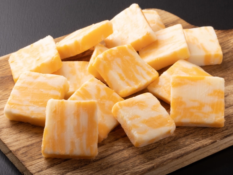 Bunch of Colby Cheese Squares on a Wooden Cutting Board