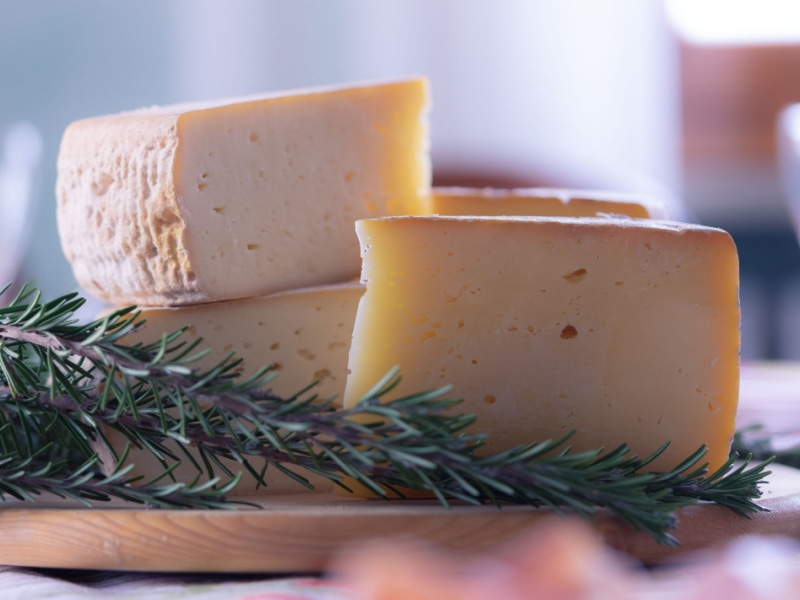 Chunks of Fontina Cheese on a Wooden Cutting Board with Rosemary
