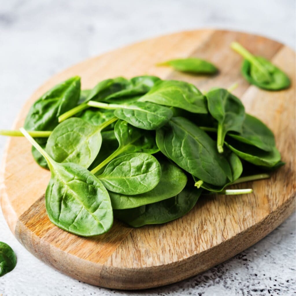 Pieces of Fresh Spinach on a Wooden Chopping Board