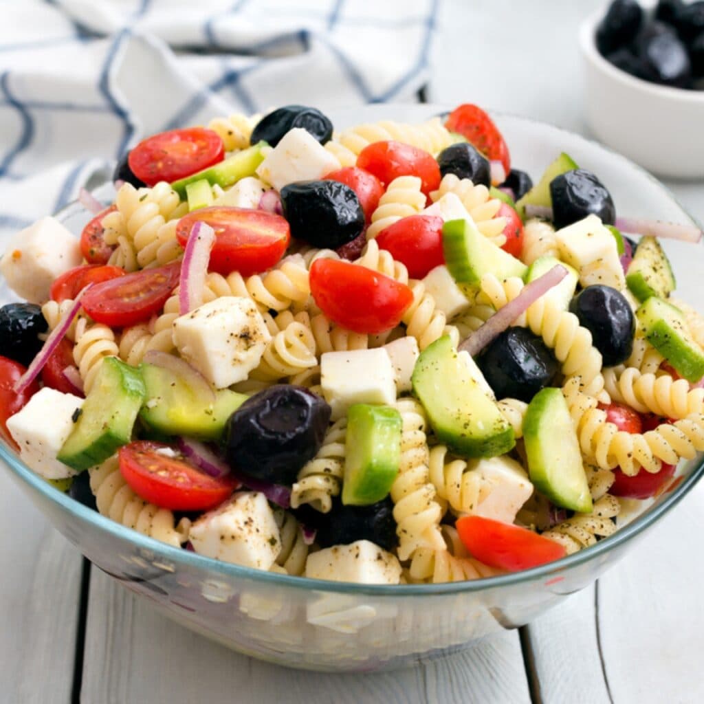 Greek Pasta Salad With Lots of Fresh Veggies and Feta Cheese in a Large Bowl on A Gray Wooden Table
