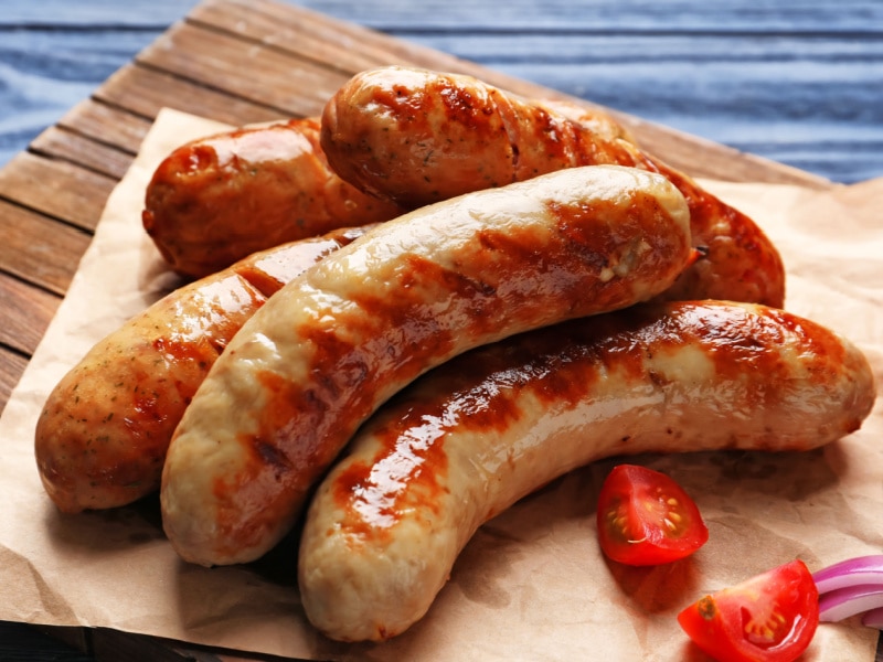 Grilled Sausages on a Parchment Paper with Tomatoes and Onions