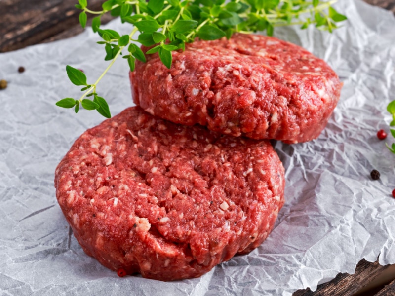 Two Ground Beef Patties with Herbs and Spices on a Parchment Paper