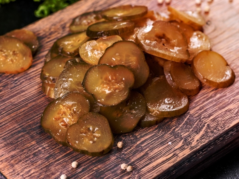 Pile of Spicy Sliced Pickles on a Wooden Cutting Board