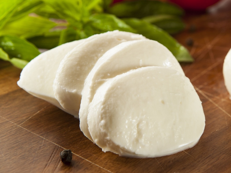 Slice Mozzarella Cheese with Herbs and Spices on a Wooden Cutting Board