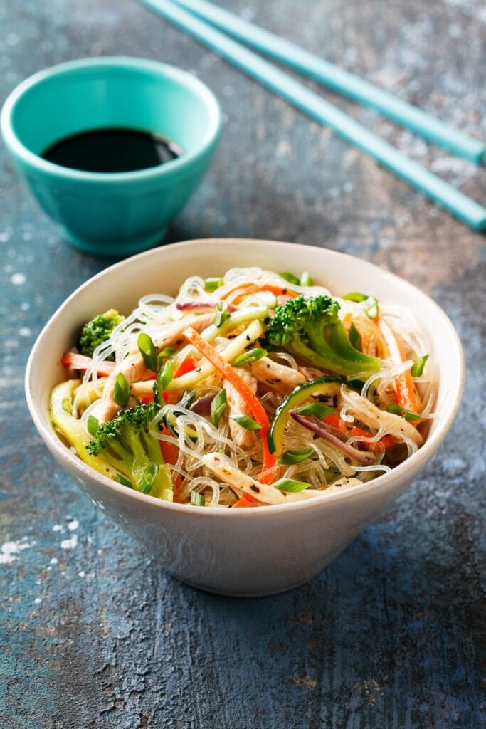 23 BEST Kelp Noodle Recipes featuring Organic Kelp Noodles with Zucchini, Carrots, Onions and Meat in a Bowl with Chopsticks and a Bowl of Sauce 