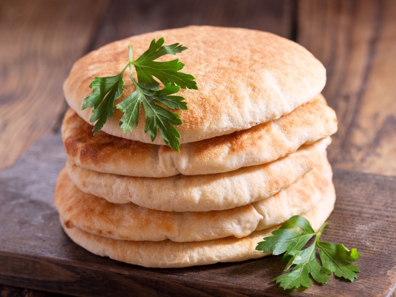 Five Stacks of Pita Bread on a Wooden Cutting Board