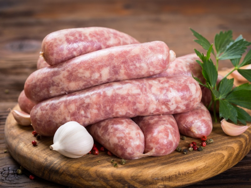 Raw Sausages with Herbs and Spices on a Wooden Cutting  Board 