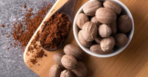 Raw Organic Nutmeg with Powder in a Wooden Board