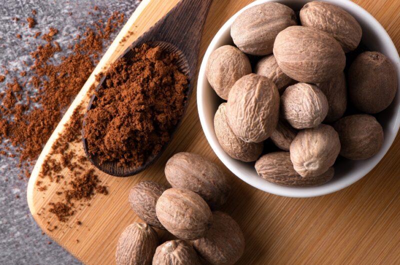 Raw Organic Nutmeg with Powder in a Wooden Board