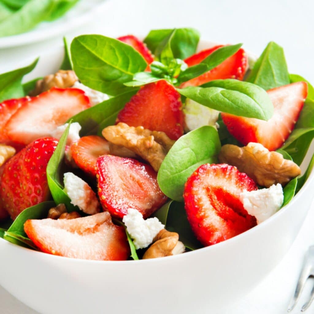 Bowl of Summer Salad With Slices of Fresh Strawberries, Spinach, Basil, Cheese and  Walnuts