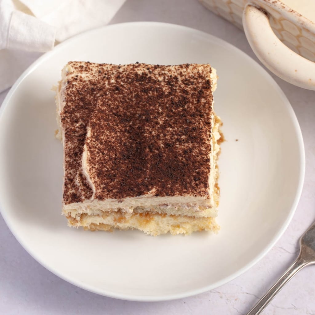 Sliced Tiramisu with Whipped Cream, Coffee and Cocoa Powder