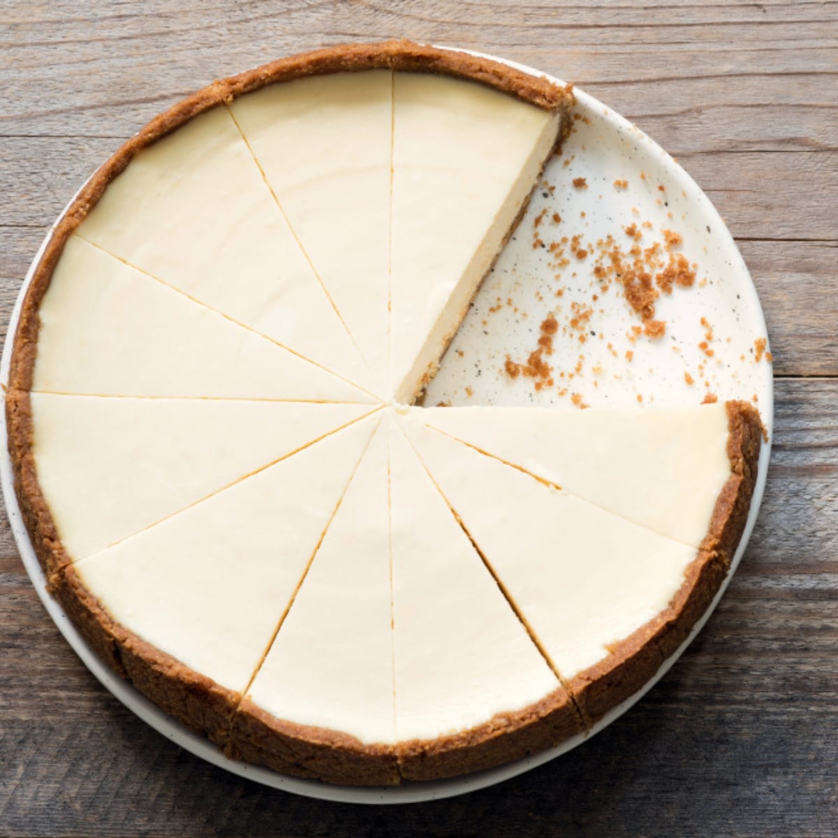 Top view of whole New York Cheesecake sliced with a piece removed