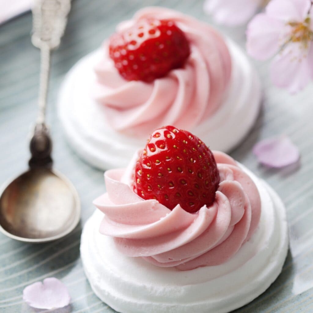 Meringue Cookies with Pink Strawberry Frosting and a Fresh Strawberry on Top