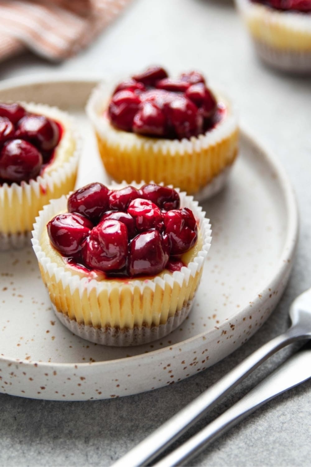 Easy Mini Cheesecakes (The Best Recipe!) featuring Mini Cheesecakes on a Plate with Cooked Cherry Topping