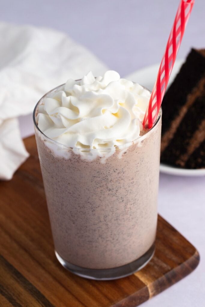Sweet and Refreshing Chocolate Cake Shake with Whipped Cream in a Wooden Board
