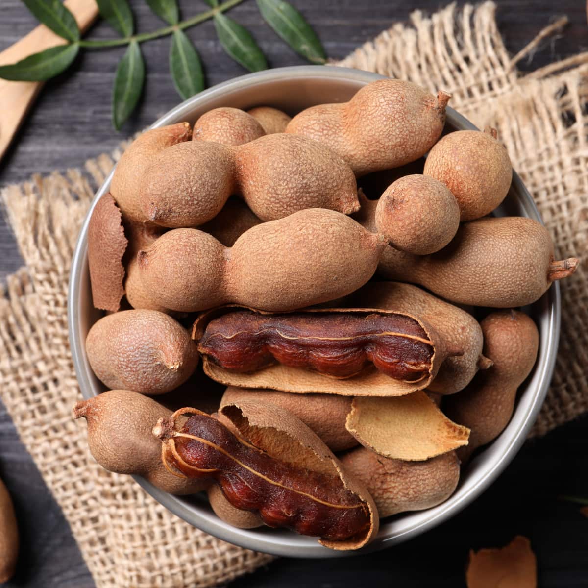 What Is Tamarind? (+ Uses & More) featuring A Bowl of Ripe Tamarinds on a Wooden Table