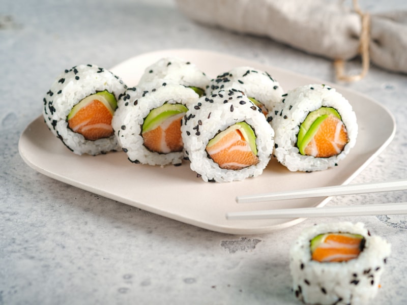 A Plater of Salmon and Avocado Uramaki Sushi on a White Plate with Chopsticks