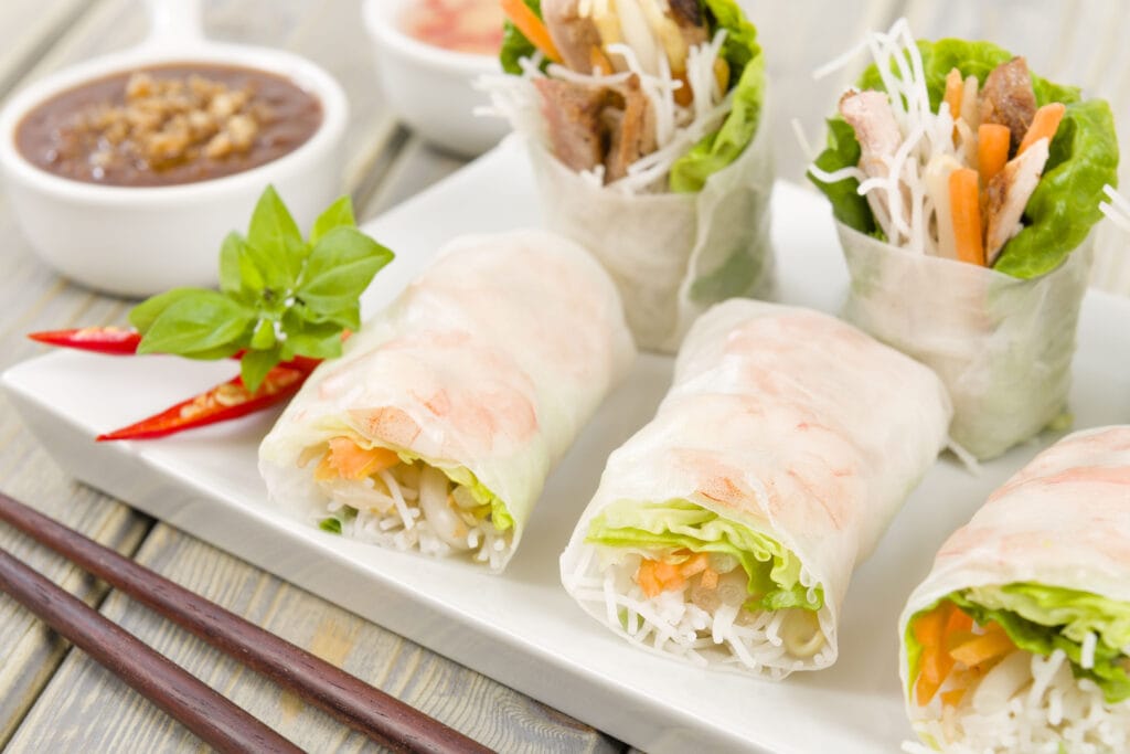 Freshly Made Vietnamese Summer Rolls  with Sauce on a Rectangle Plate on a Wooden Table