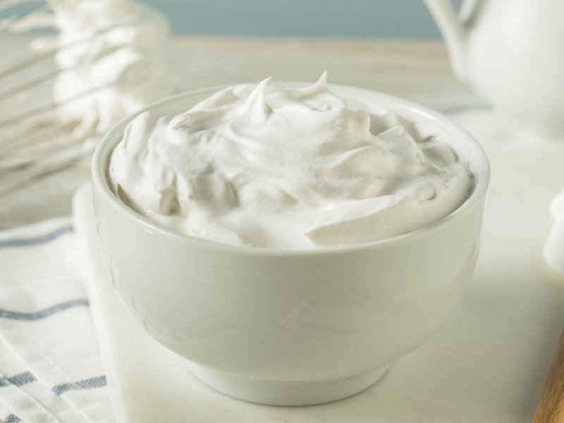 A Bowl of Whipped Cream on a Table with Whisk