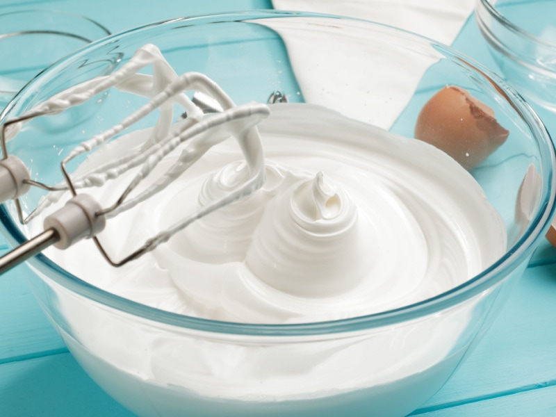 Whipped Cream on Glass Bowl with Whisk on a Wooden Table