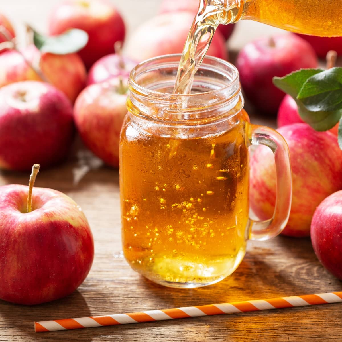 Fresh Apple Juice Pouring From Bottle Into Glass Jar