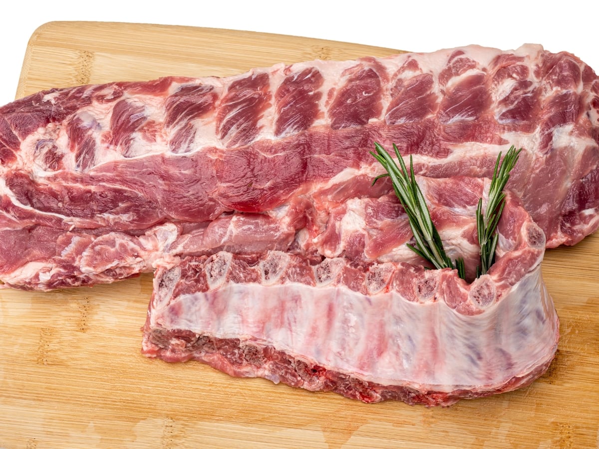 Raw, Marbled Baby Back Ribs with Rosemary on a Wooden Cutting Board