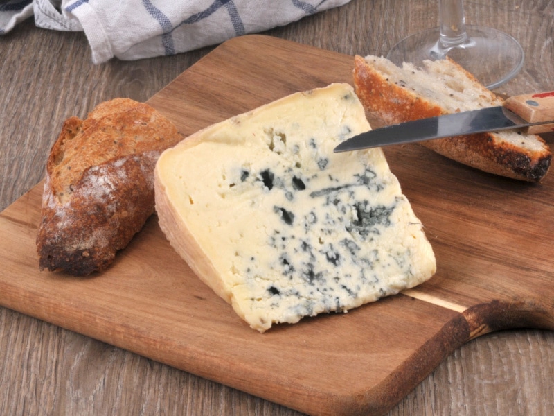 Slice of Bleu d’Auvergne Cheese and Bread on a Wooden Cutting Board