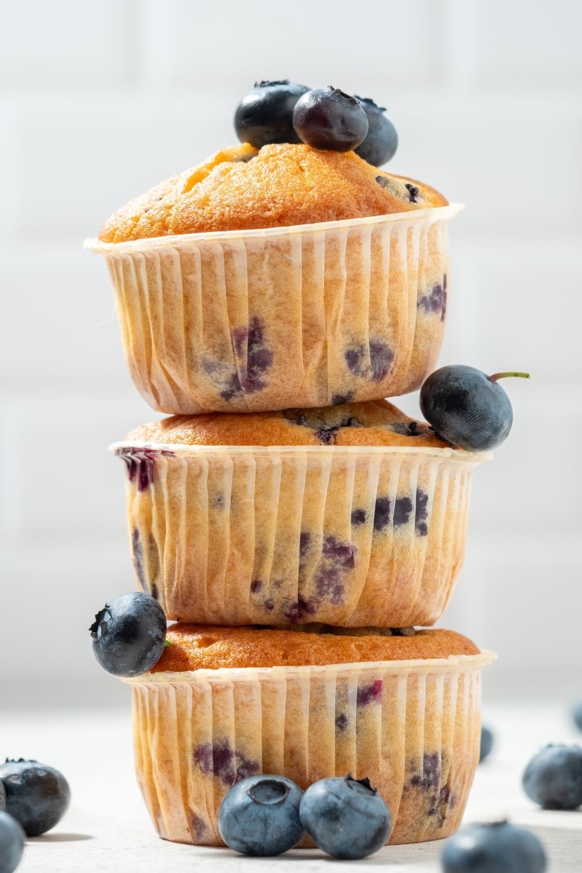 Jordan Marsh Blueberry Muffins (Copycat) featuring Two Fresh Baked Homemade Jordan Marsh Blueberry Muffins Stacked One on Another with Fresh Blueberries