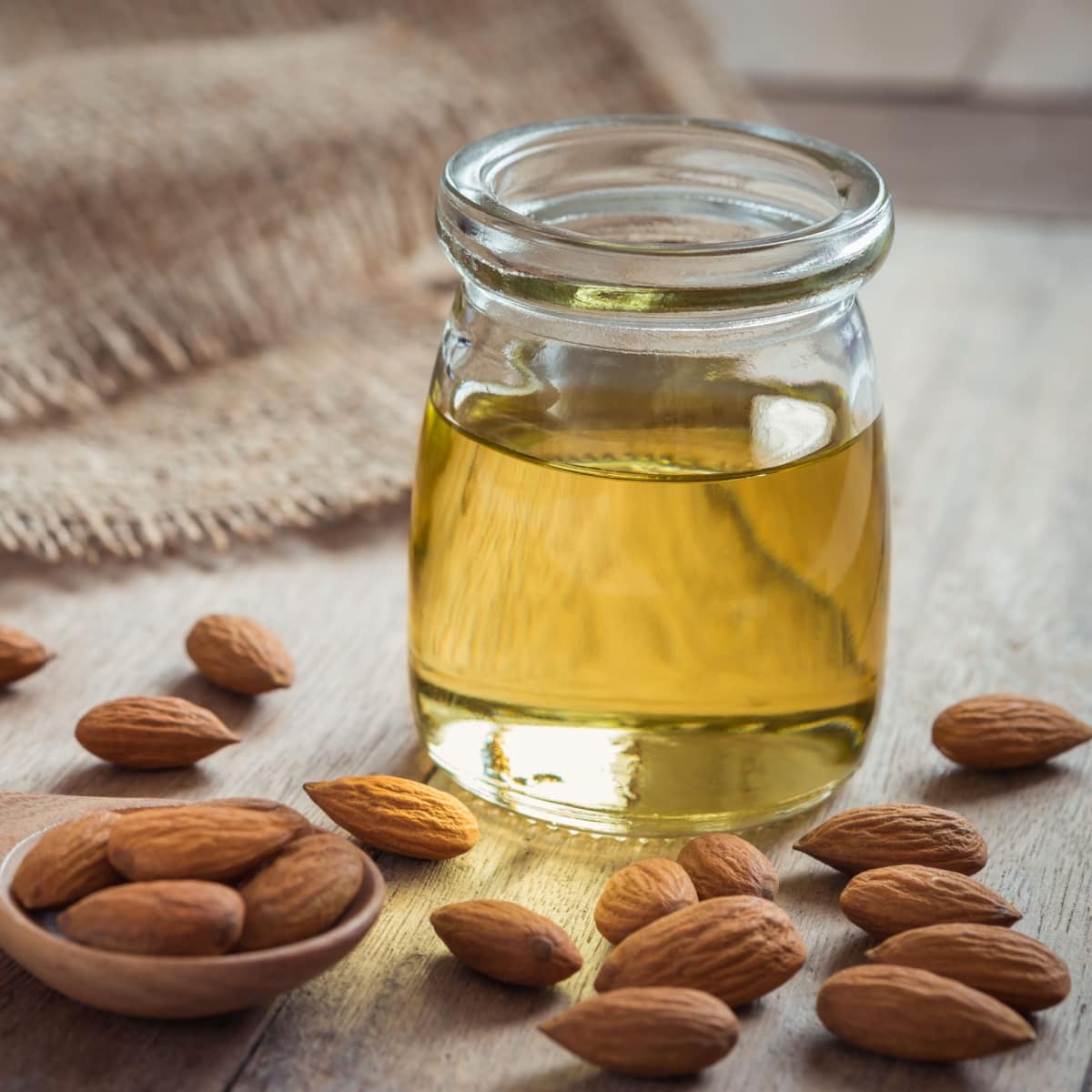 Bottle of Almond Oil and Raw Almonds on a Wooden Table