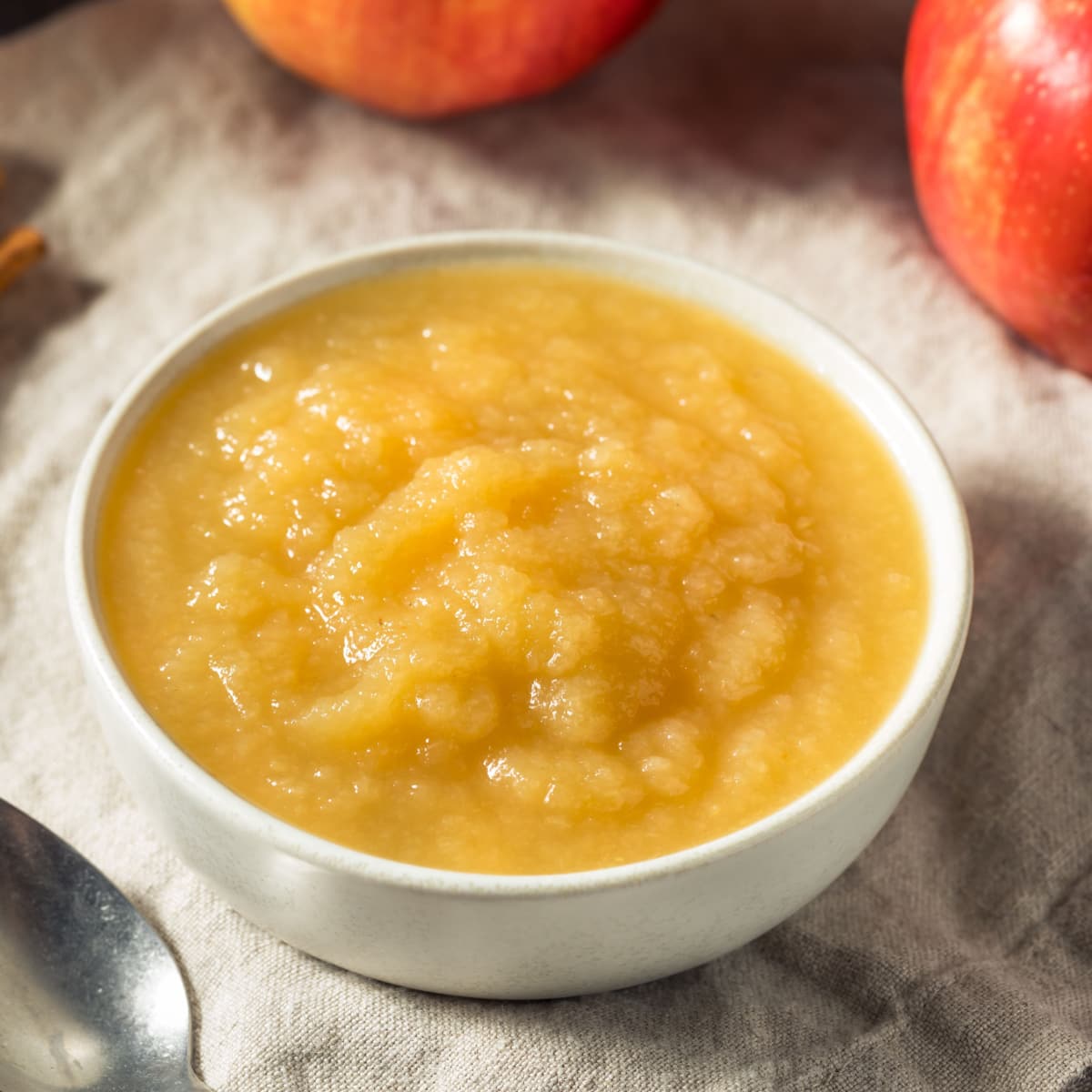Bowl of Applesauce and Fresh Apples on a Rustic Cloth