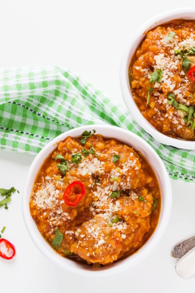 25 Easy 400-Calorie Meals for Mindful Eating featuring Two Bowls of Homemade Spicy Lentil Meatball Soup on a Green Gingham Cloth