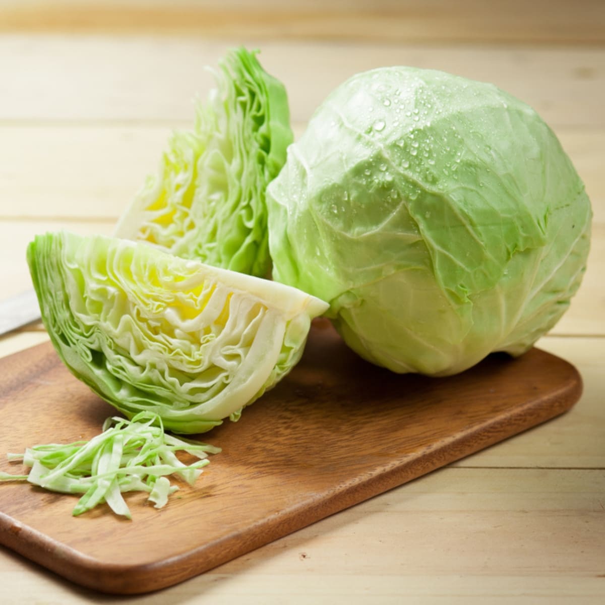 Whole and Sliced Cabbage on a Wooden Chopping Board