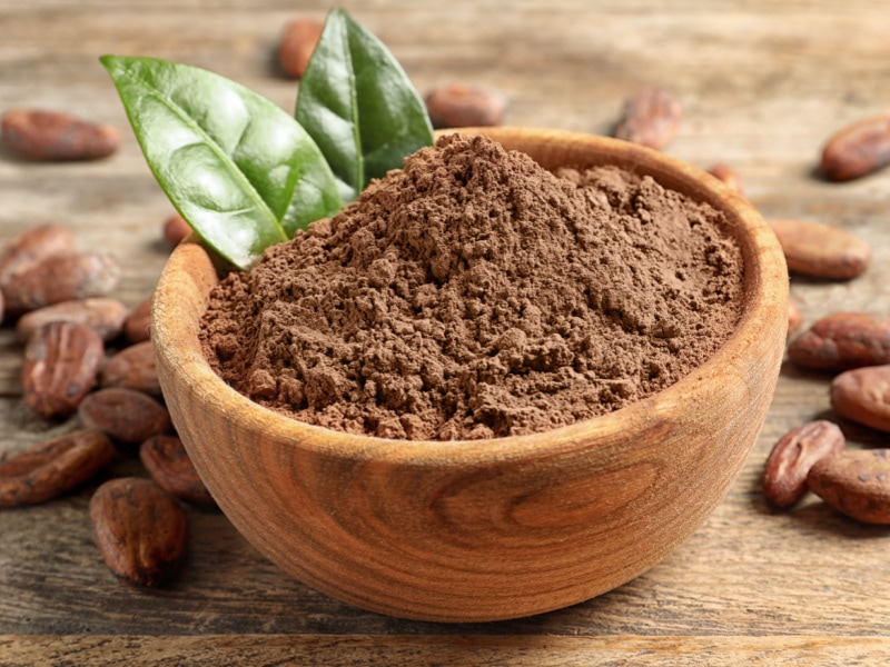 Bowl of Cocoa Powder and Cacao Beans on a Wooden Table