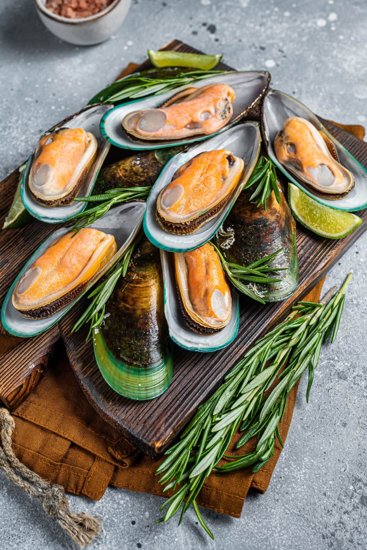 Cooked Green Mussels with Lime and Thyme Leaves on a Wooden Cutting Board
