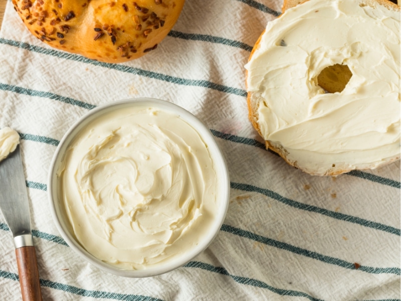 Tub of cream cheese and bagel with cream cheese
