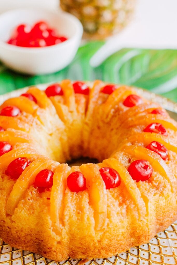 The Best Pineapple Upside-Down Bundt Cake featuring Close-Up of Fresh Baked Pineapple Upside-Down Bundt Cake on a White and Gold-Patterned Serving Tray