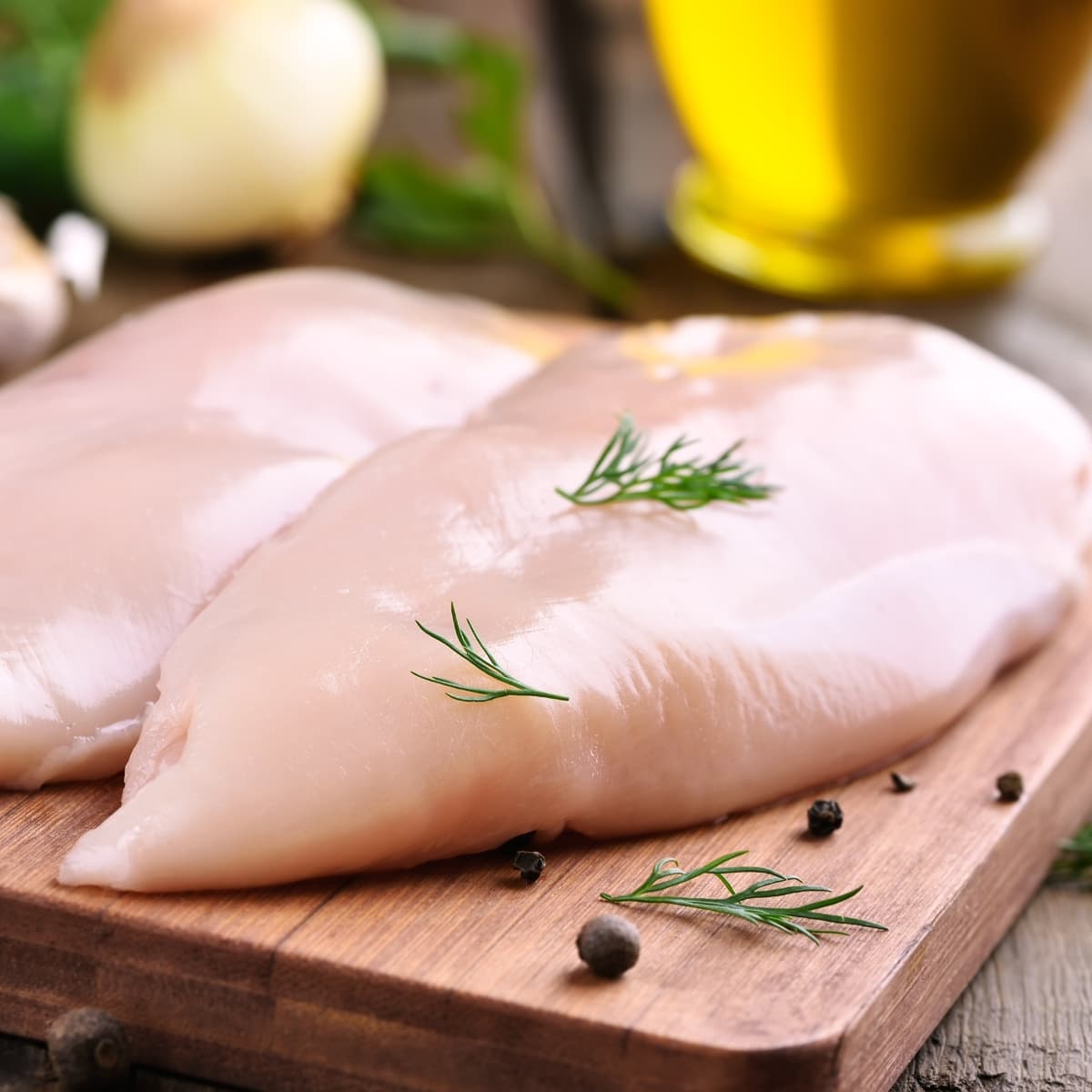 Fresh Raw Chicken Breasts on a Wooden Board