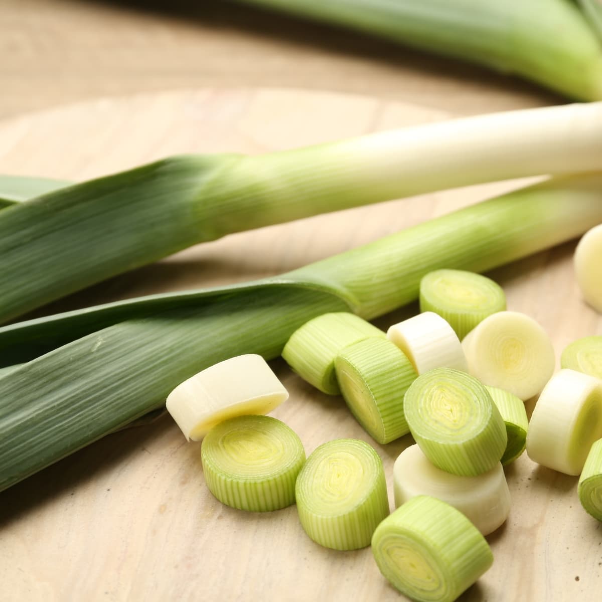 Whole And Cut Fresh Leeks On Wooden Table