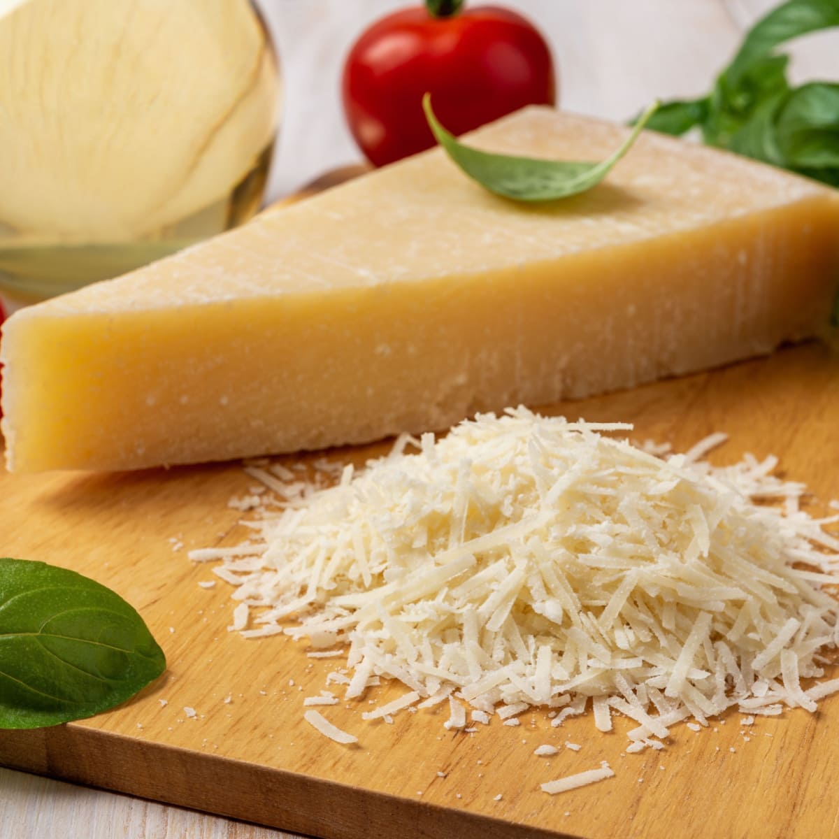 Grated Grana Padano and Wedge Cheese with Tomatoes on a Wooden Cutting Board
